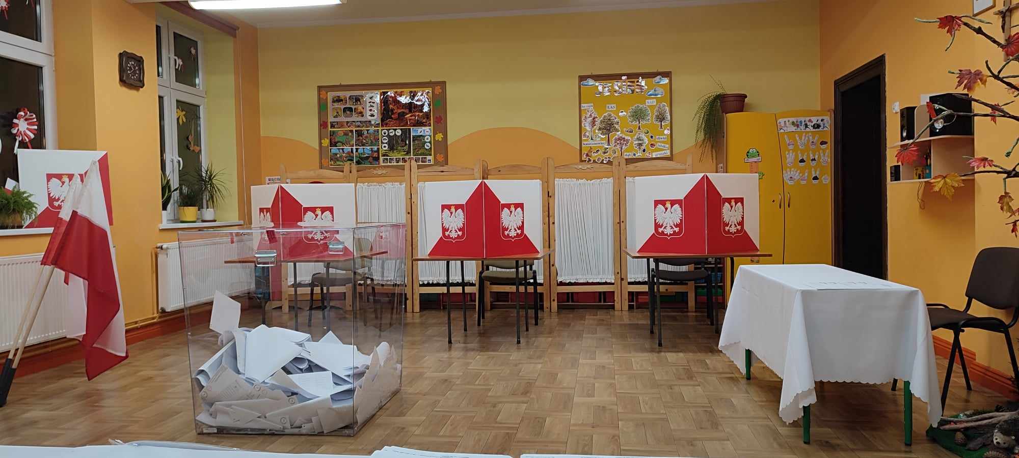 Zdjęcie przedstawia lokal wyborczy w Osłoninie. Na zdjęciu widoczne są urna wyborcza oraz miejsca przeznaczone do głosowania.