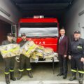 Zdjęcie przedstawia trzech strażaków, którzy trzymają nowe stroje. Na zdjęciu także wójt.