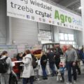 Zdjęcie przedstawia ludzi wchodzących na targi. U góry wisi billboard na którym jest napisane: "Żeby wiedzieć trzeba czytać Agro".