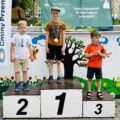 Zdjęcie przedstawia trójkę chłopców stojących na podium. Jeden z nich ma złoty medal.