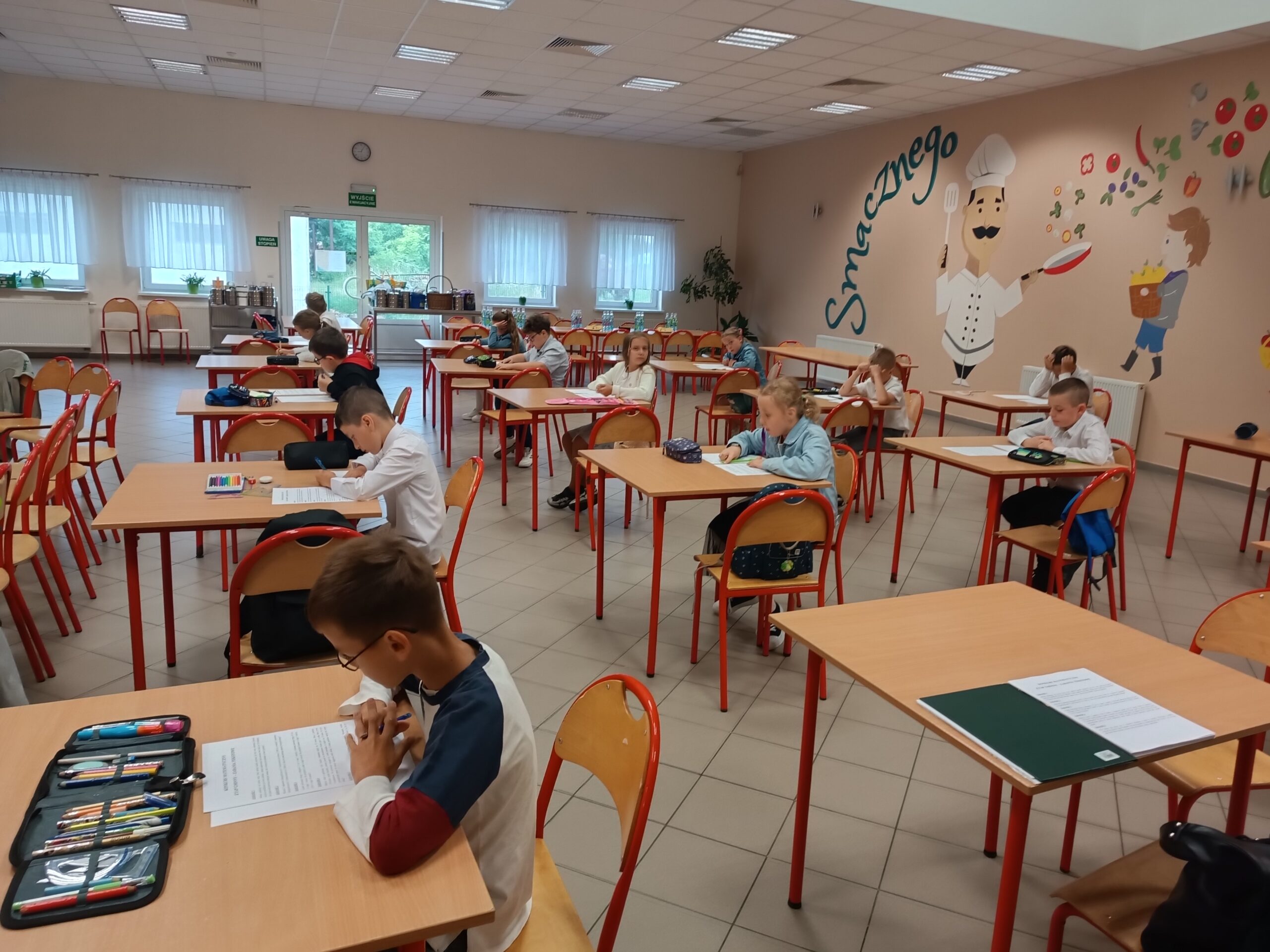 Na zdjęciu dzieci w ławkach podczas pisania testu konkursowego.