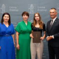 Na zdjęciu dziewczyna, która otrzymała nagrodę wójta za osiągnięcia w biegu na orientację. Na zdjęciu także rodzic nagrodzonej, wójt oraz przewodnicząca Rady Gminy Przemęt. Wszyscy pozują na tle dużej ścianki Gminy Przemęt.