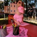 Na zdjęciu dziewczynka ubrana cała na różowo koloruje kolorowanki o tematyce strażackiej
