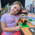 Dziewczynka pozuje do zdjęcia z konstrukcją lego.