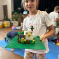 Dziewczynka pozuje do zdjęcia z konstrukcją lego.