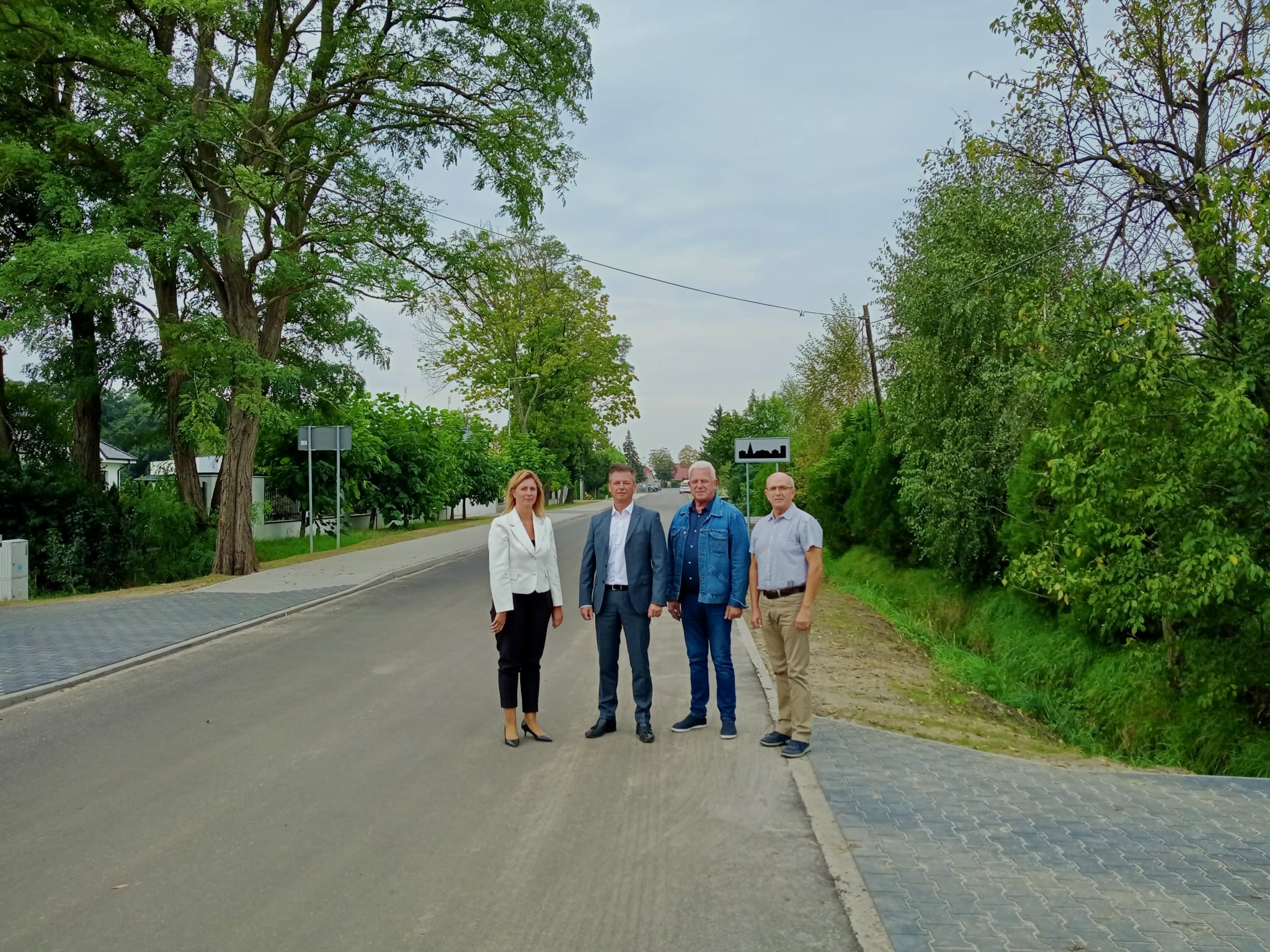 Wspólne zdjęcie na tle drogi wszystkich zebranych na odbiorze osób.