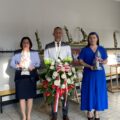 Na zdjęciu delegacja w składzie: wójt, przewodnicząca rady gminy oraz skarbnik gminy. Wójt trzyma wiązankę, a przewodnicząca i skarbnik znicze.