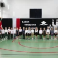 Na zdjęciu uczniowie szkoły podstawowej w Przemęcie podczas uroczystości rozpoczęcia roku szkolnego. W tle ścianka, na której widnieje napis "Razem tworzymy historię".