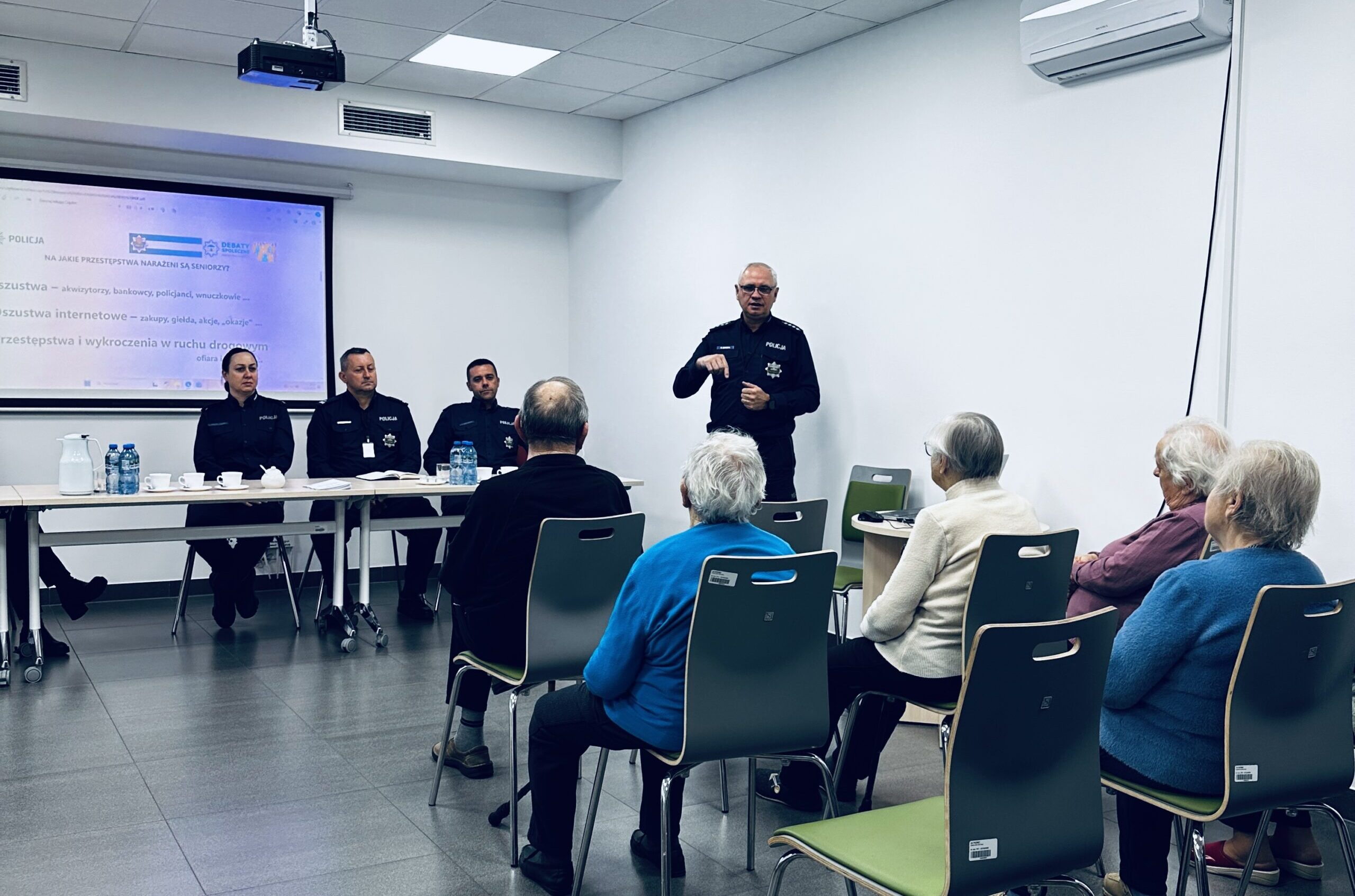 Na zdjęciu policjant podczas omawiania seniorom przygotowanej prezentacji.
