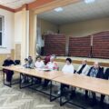 Na zdjęciu osoby przybyłe na spotkanie oraz organizatorzy siedzący przy stole.
