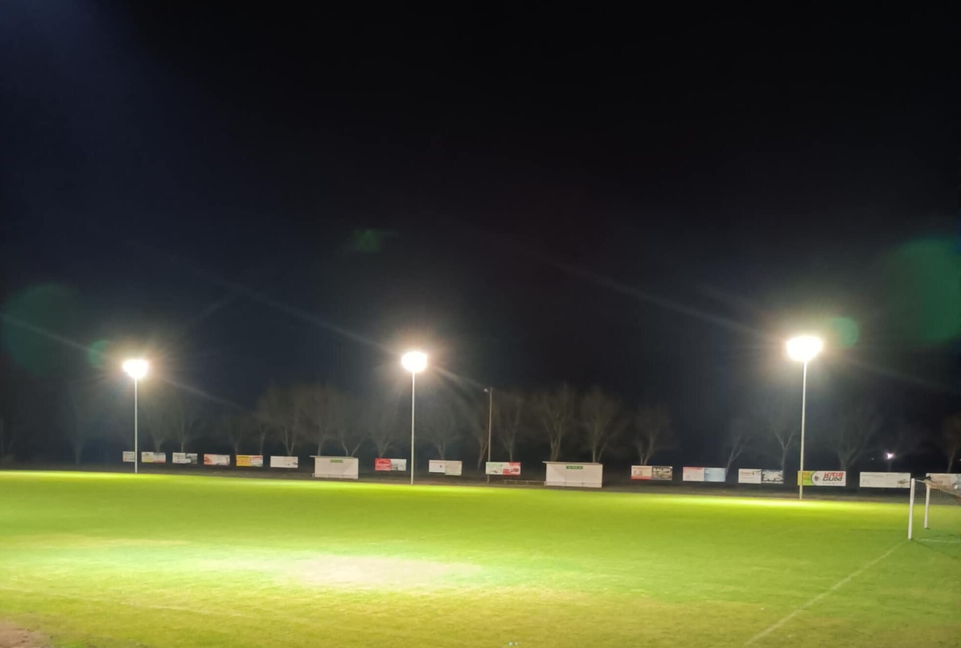 Zdjęcie przedstawia oświetlony stadion po zmroku.