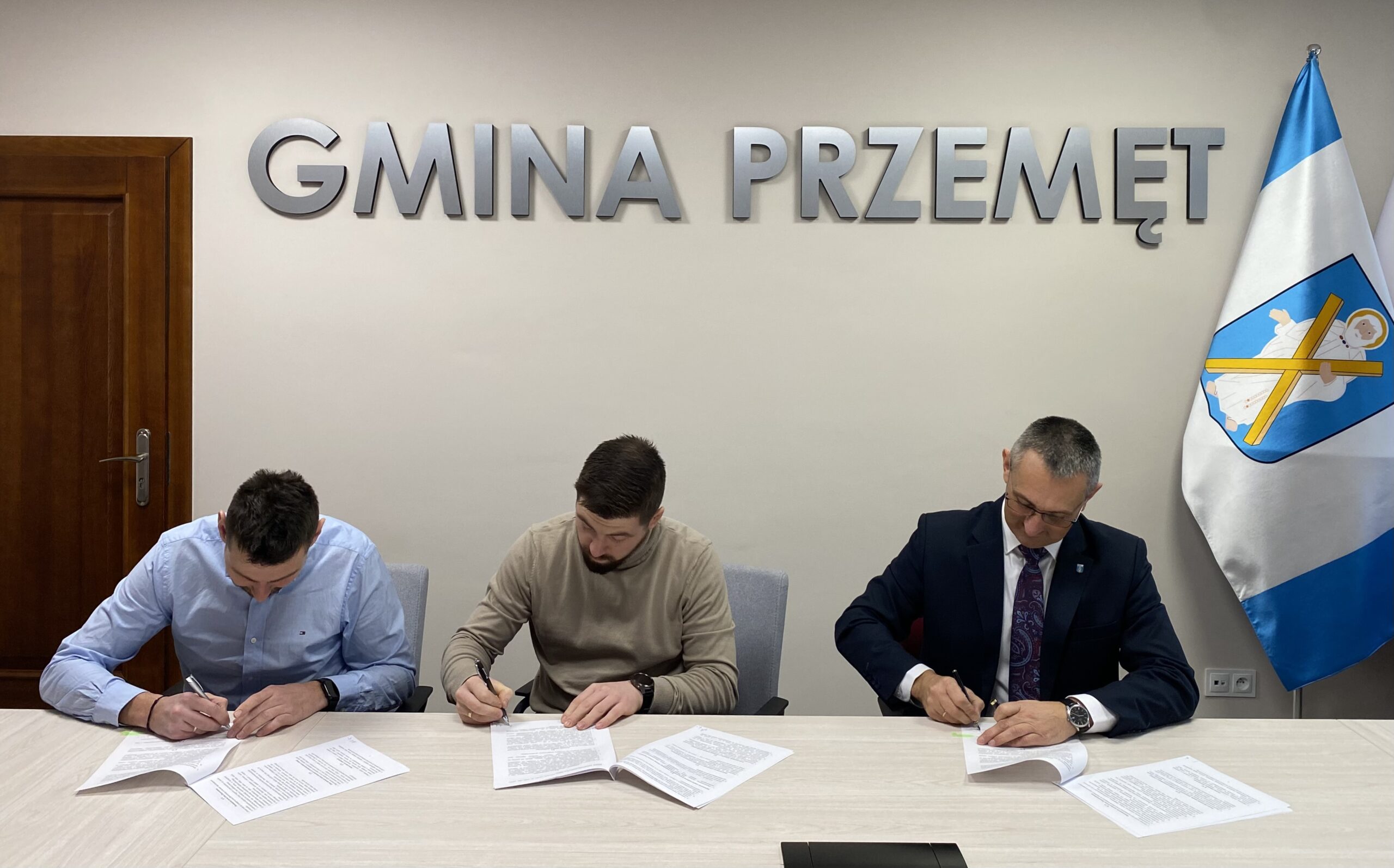 Na zdjęciu wójt oraz dwóch przedstawicieli klubu Sporting Przemęt podczas podpisywania umowy. W tle srebrny napis: "GMINA PRZEMĘT".
