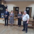 Na zdjęciu wójt Janusz Frąckowiak, który trzyma list gratulacyjny oraz kwiaty. Na fotografii także sołtys Popowa Starego podczas wygłaszania przemowy oraz dwie kobiety.