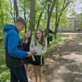 Uczeń i dwie uczennice wykonują zadanie konkursowe na świeżym powietrzu.