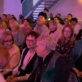 Na zdjęciu osoby siedzące na widowni i rozmawiające.