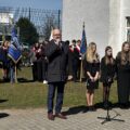 Na fotografii dyrektor szkoły podstawowej z Bucza przemawia podczas uroczystości. W tle poczty sztandarowe z pobliskich szkół.