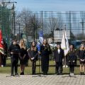 Na fotografii uczniowie prowadzący uroczystość. W tle poczty sztandarowe.