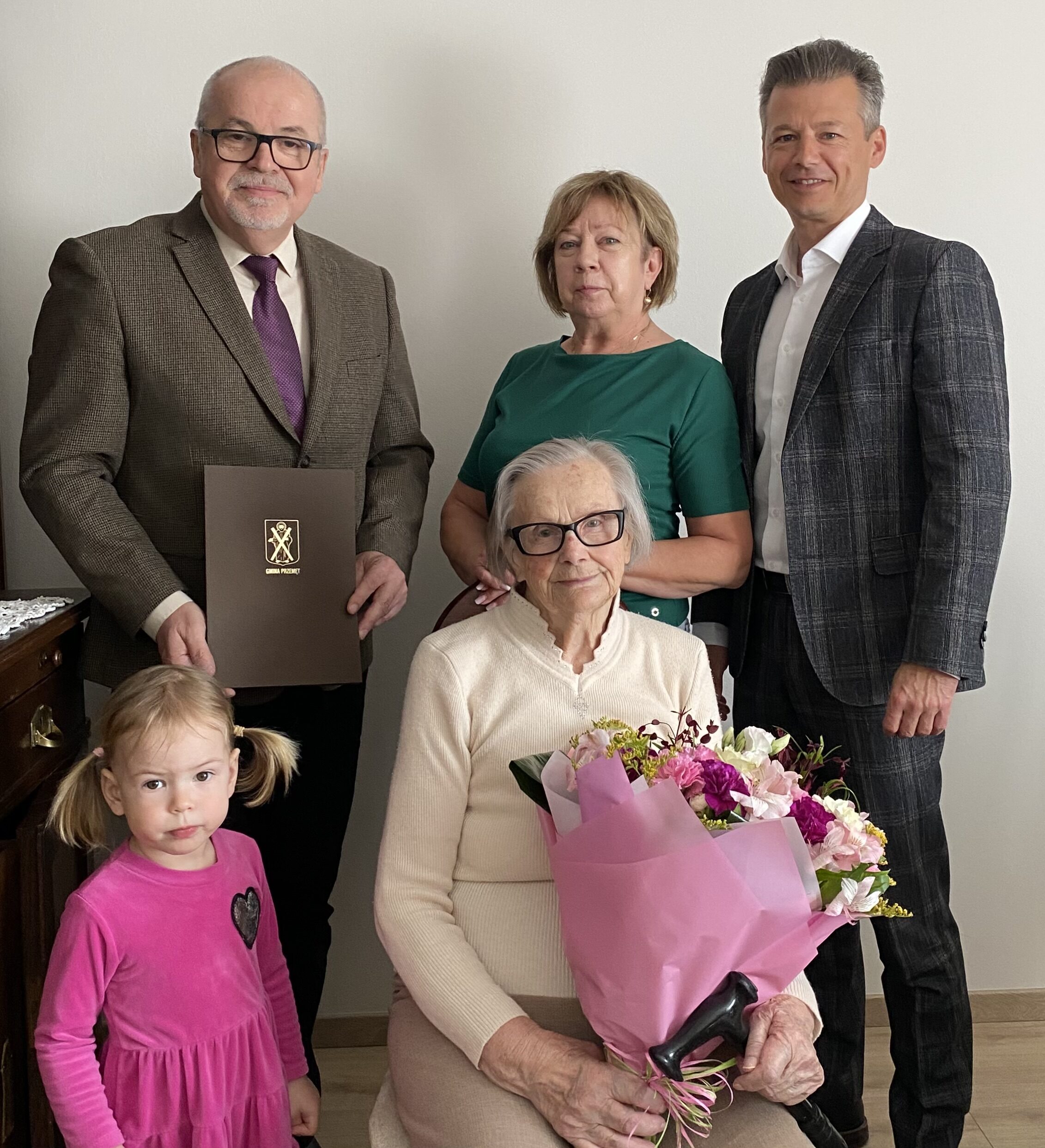 Na zdjęciu Zastępca Wójta Waldemar Kalitka, Pan Leszek Anglart, Pani Irena wraz z jej synową oraz prawnuczką. Pani Irena trzyma bukiet kwiatów, a Pan Leszek list gratulacyjny dla jubilatki.