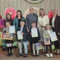 Wspólne zdjęcie na tle wystroju sceny. Na zdjęciu m.in. przewodnicząca rady gminy Przemęt Monika Maćkowiak, dyrektor szkoły i przedszkola Dagmara Nowak, kierownik wydziału oświaty i sportu Marta Sobierajska, zastępca dyrektora GCKiB Elwira Michalewicz, a także czwórka zwycięzców, którzy pozują z dyplomami i nagrodami.