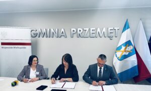 Na zdjęciu widoczna Pani Karolina Fabiś-Szulc wicewojewoda wielkopolski, Janusz Frąckowiak wójt gminy Przemęt oraz Bożena Ćwiklińska skarbnik gminy Przemęt. Na fotografii wójt i wicewojewoda podczas podpisywania umowy. W tle srebrny napis: Gmina Przemęt, roll up z napisem Wojewoda Wielkopolski oraz flaga Polski i flaga europejska.