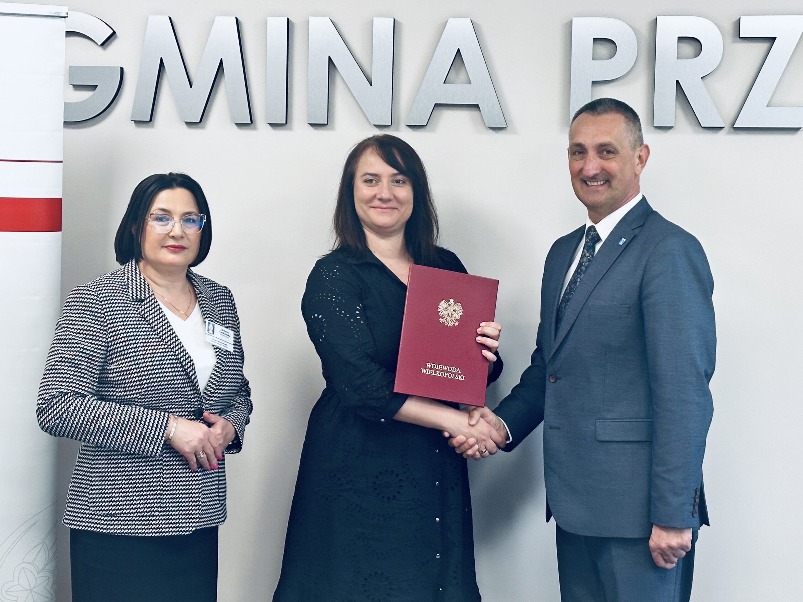 Na zdjęciu widoczna Pani Karolina Fabiś-Szulc wicewojewoda wielkopolski, Janusz Frąckowiak wójt gminy Przemęt oraz Bożena Ćwiklińska skarbnik gminy Przemęt. Wójt oraz wicewojewoda podają sobie dłoń. Pani Karolina trzyma teczkę z napisem Wicewojewoda Wielkopolski, w której znajduje się podpisana umowa.