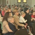 Na zdjęciu kobiety siedzące z dziećmi na widowni.