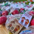 Zdjęcie przedstawia upominki dla uczestników. Do upominków zostały przywieszone karteczki, na których znajdują się postacie dwóch młodych strażaków i napis: "Gminne Zawody Dziecięcych Drużyn Pożarniczych, 28.06.2025 Starkowo".