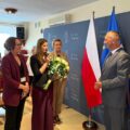 Na fotografii delegacja złożona z trzech kobiet pracujących w urzędzie gminy. Na zdjęciu uchwycono moment składania życzeń przez kierownik wydziału organizacyjnego Liwię Sternę, która trzyma także bukiet białych róż, by wręczyć je wójtowi.