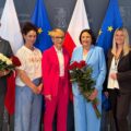 Na zdjęciu wójt, zastępca wójta oraz skarbnik gminy Przemęt. Wyżej wymienione osoby pozują do zdjęcia z bukietami róż. Na zdjęciu znajduje się także p.o. dyrektora GCKiB Agnieszka Klugiewicz, zastępca dyrektora Elwira Michalewicz oraz dyrektor GOPSu Barbara Ścigała. Wszyscy pozują na tle ścianki "Gmina Przemęt" oraz flag: dwóch flag Polski i dwóch Europejskich.