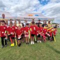 Grupowe zdjęcie jednej z drużyn. Dzieci pozują do zdjęcia z medalami i nagrodami. Na fotografii także organizatorzy i niektórzy zaproszeni goście.