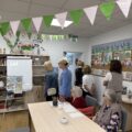 Na fotografii delegacja z Miedzichowa zwiedza główną salę. Na zdjęciu także dwie seniorki, które siedzą przy stole.
