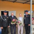 Na fotografii osoby obecne na uroczystości. Dwójka mężczyzn trzyma bukiety kwiatów.