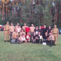 Grupowe zdjęcie drużyn, które pozują z dyplomami, pucharami i czekami.