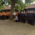 Na fotografii widoczni strażacy oraz osoby z orkiestry dętej. Na zdjęciu także wójt Janusz Frąckowiak. Wszyscy stoją na zewnątrz.