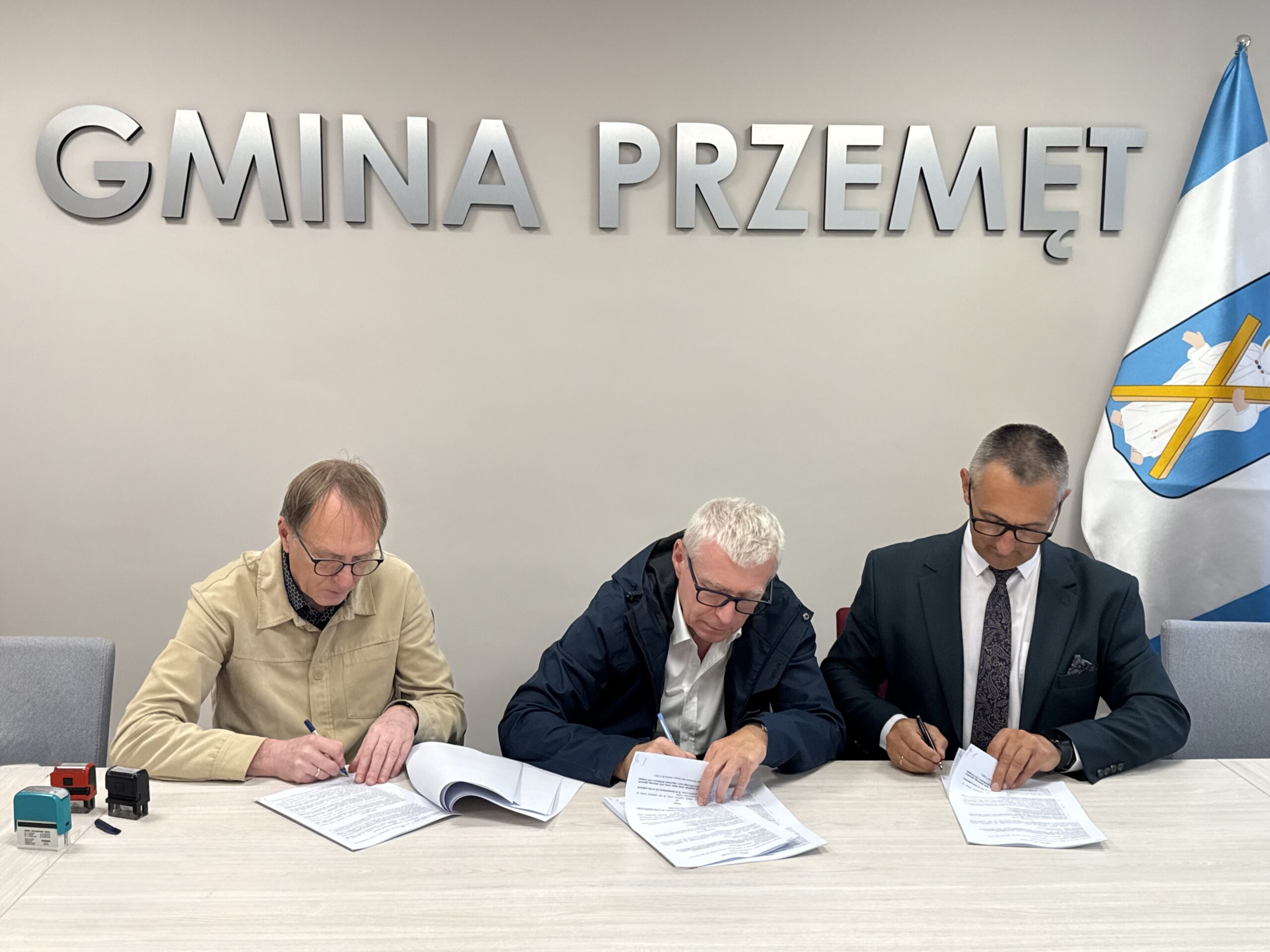Na fotografii wójt i dwóch innych mężczyzn podczas podpisywania umowy. W tle srebrny napis: "Gmina Przemęt".