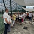 Na fotografii widoczni są seniorzy oraz wicedyrektor szkoły w Kaszczorze. Seniorzy zwiedzają boisko szkolne.