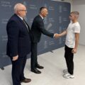 Na fotografii wójt składa gratulacje absolwentowi technikum. Na zdjęciu także dyrektor szkoły z Przemętu. W tle ścianka gminy.