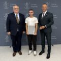 Na zdjęciu wójt, absolwent technikum, który pozuje z listem gratulacyjnym oraz dyrektor szkoły z Przemętu. W tle ścianka gminy.