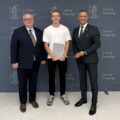 Na zdjęciu wójt, absolwent technikum, który pozuje z listem gratulacyjnym oraz dyrektor szkoły z Przemętu. W tle ścianka gminy.