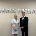 Wójt pozuje do zdjęcia z jedną z mianowanych nauczycielek. Kobieta trzyma akt mianowania w ręce. w tle srebrny napis "Gmina Przemęt" oraz flaga z herbem gminy.