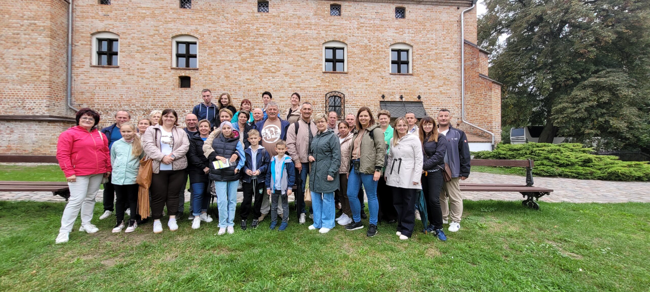 Grupowe zdjęcie uczestników wycieczki. Na fotografii także wójt Janusz Frąckowiak. Wszyscy pozują przed Muzeum Zamek Opalińskich.