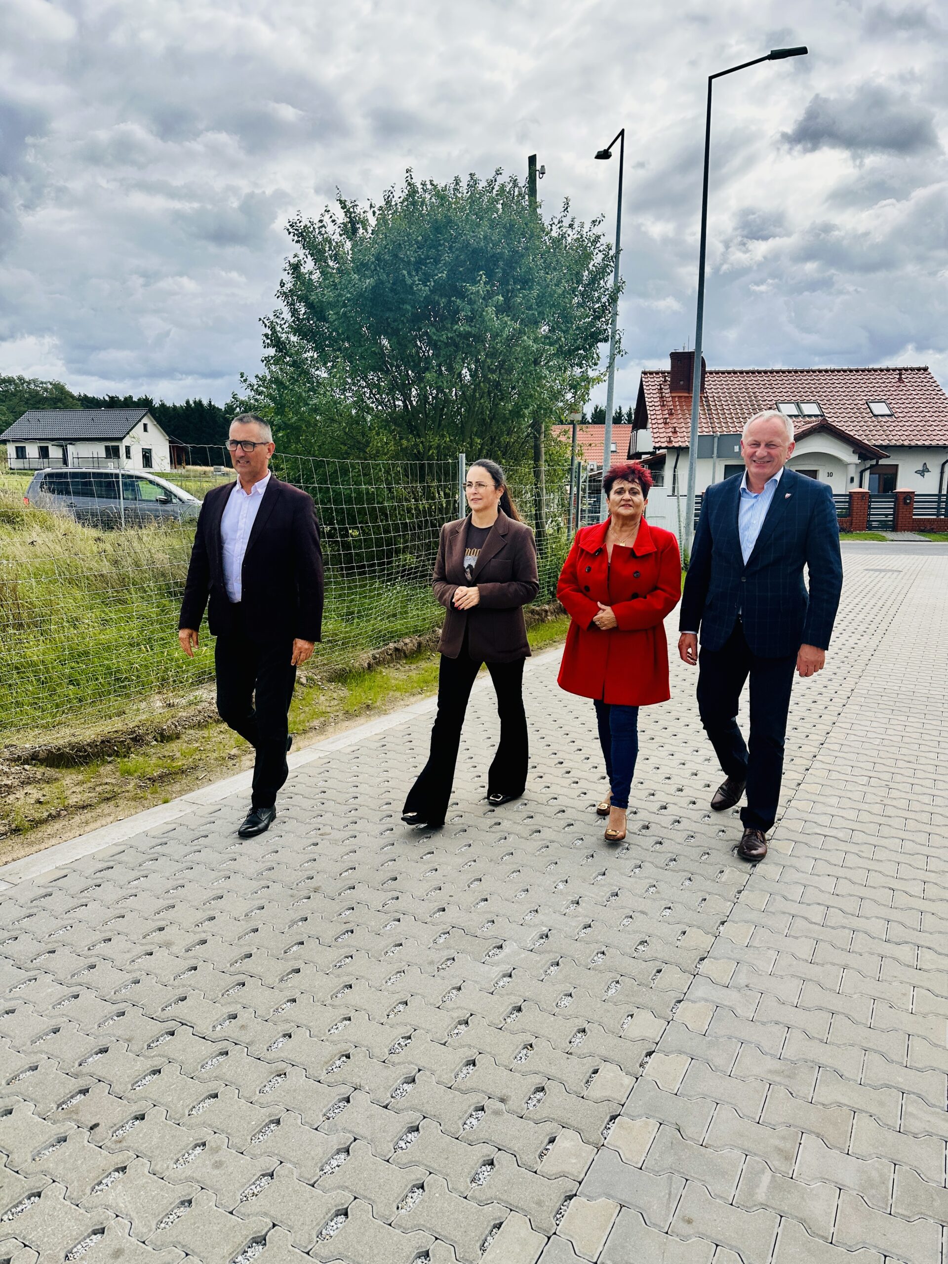 Na fotografii wójt gminy Przemęt Janusz Frąckowiak, radna gminy Przemęt Kinga Piędel, Prezes PPK Sp. z o.o. Józef Kwaśniewicz oraz sołtys Kaszczoru Beata Binkowska. Wyżej wymienione osoby idą nowo wybudowaną ulicą Wiatrakową w miejscowości Kaszczor.