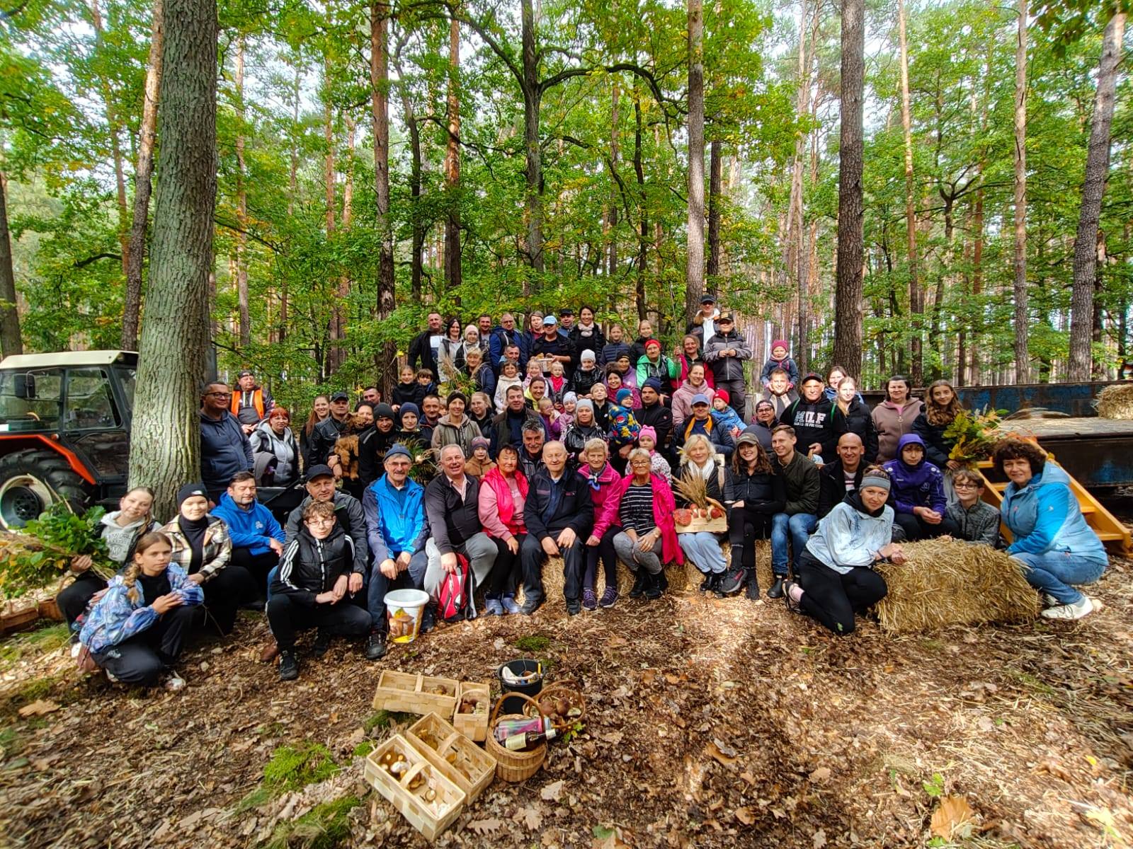 Grupowe zdjęcie wszystkich uczestników grzybobrania. Fotografię wykonano w lesie.