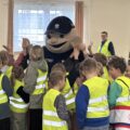 Na zdjęciu widoczna policyjna maskotka "Pyrek", która przybija piątki z uczniami.