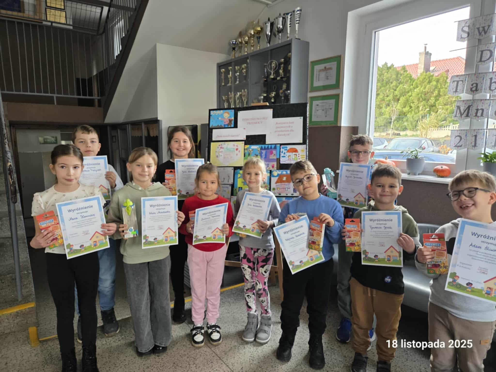 Grupowe zdjęcie uczniów, którzy wzięli udział w konkursie. Uczniowie pozują z dyplomami.