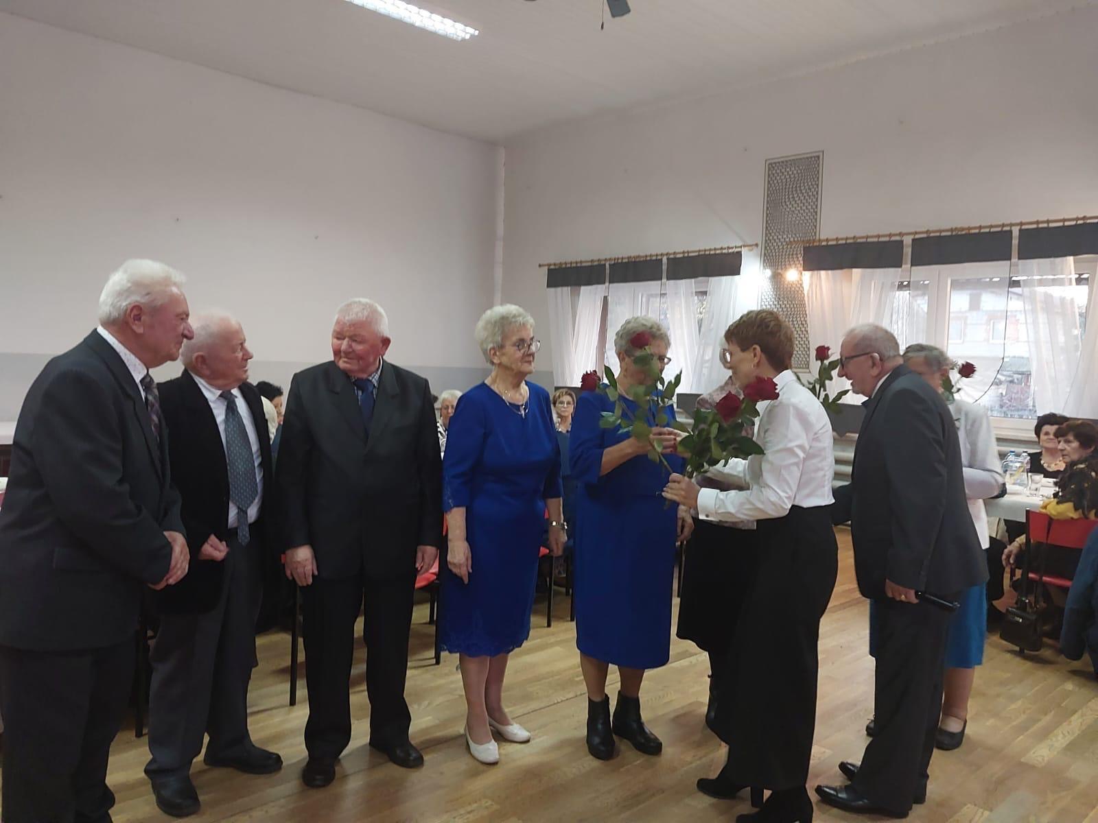 Na zdjęciu widoczna Barbara Ścigała, która wręcza róże seniorom.