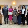 Wspólne zdjęcie, na którym jest wójt, przewodnicząca rady gminy, dyrektor GCKiB, zastępca dyrektora GCKiB, przewodnicząca rady gminy oraz przewodnicząca KGW z dwiema członkiniami KGW. Przewodnicząca pozuje z promesą, a dwie kobiety z listem gratulacyjnym i bukietem kwiatów.
