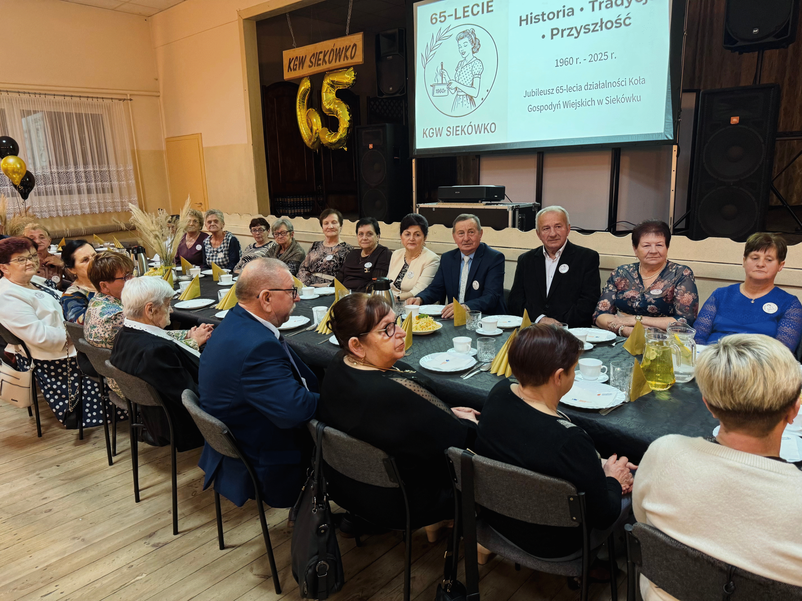 Na zdjęciu seniorzy siedzący przy stole.