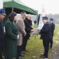 Zdjęcie przedstawia wręczenie obrazu panu Wiesławowi Szczepańskiemu przez druha Roberta Pawłowskiego. Obraz przedstawia nowy samochód strażacki. Na fotografii także wójt gminy, przewodnicząca rady gminy oraz komendant PSP w Wolsztynie.