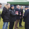 Zdjęcie przedstawia wręczanie przez strażaków statuetek zasłużonym osobom.